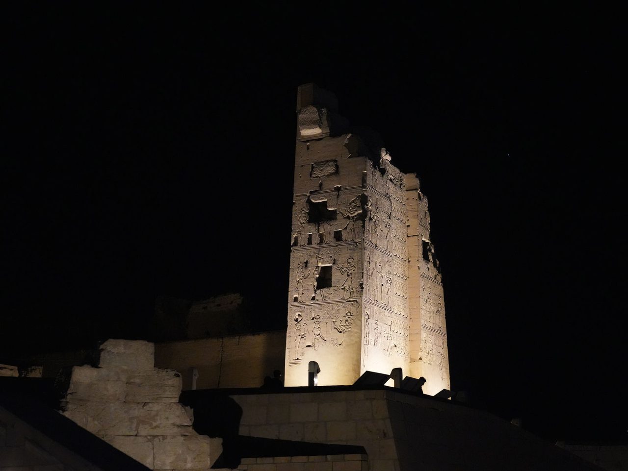 The majestic illuminated tower of the Temple of Kom Ombo rising into the dark night