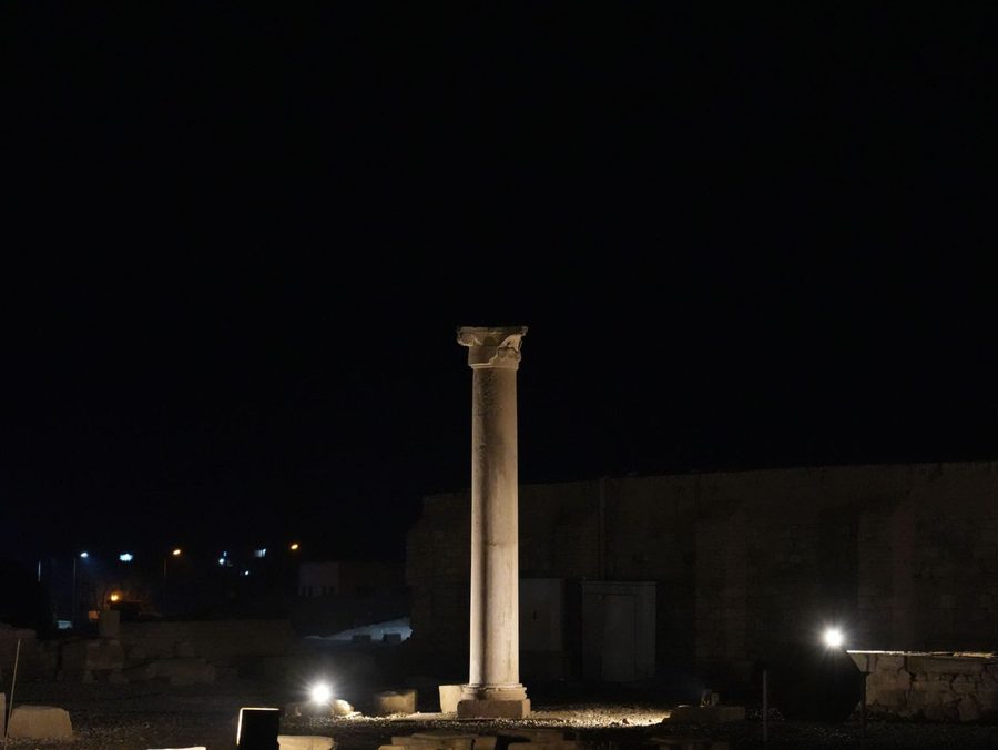 A lone ancient column standing proud under the dark night sky