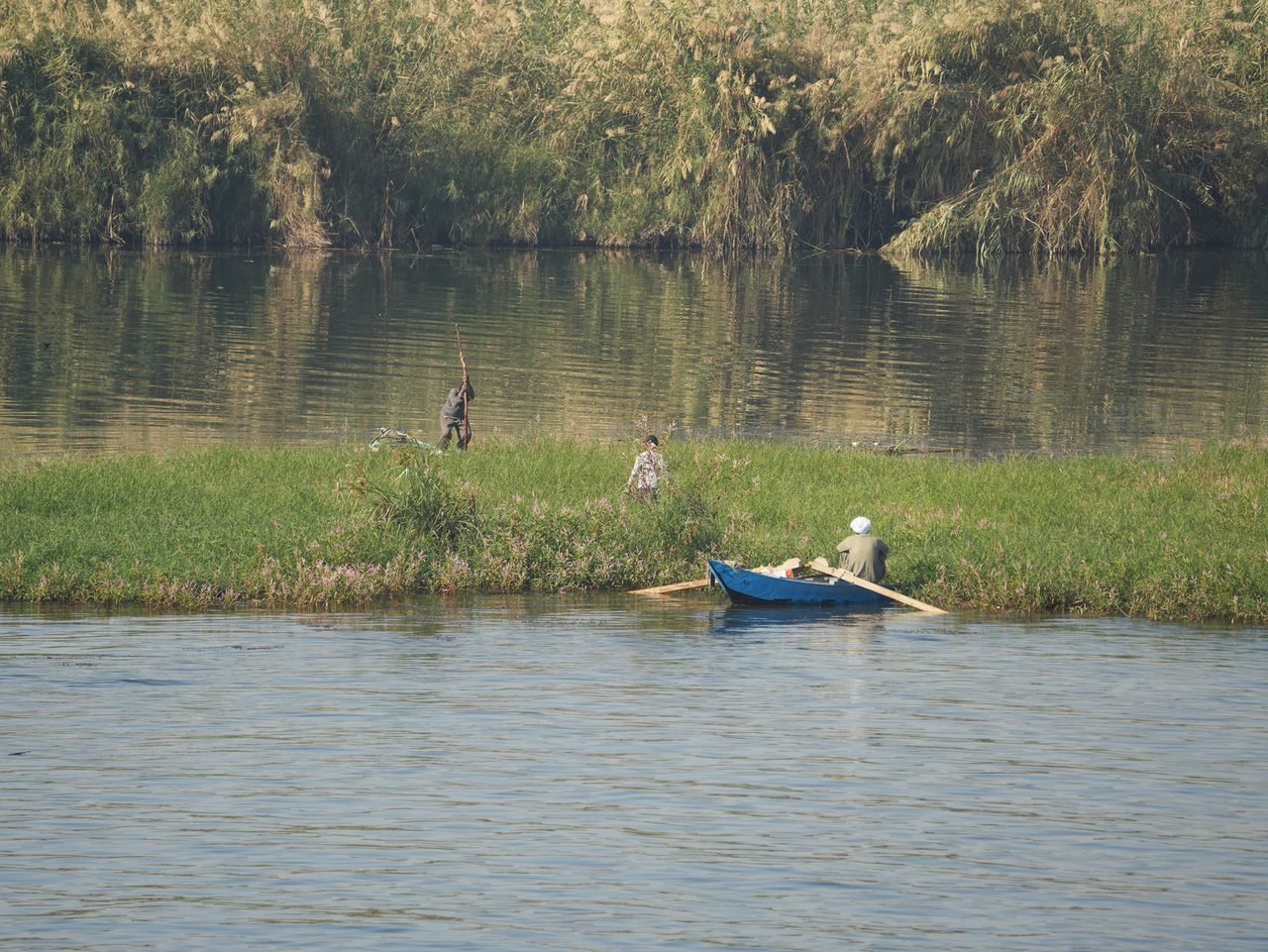 Local fishermen and a small blue boat on the calm Nile River