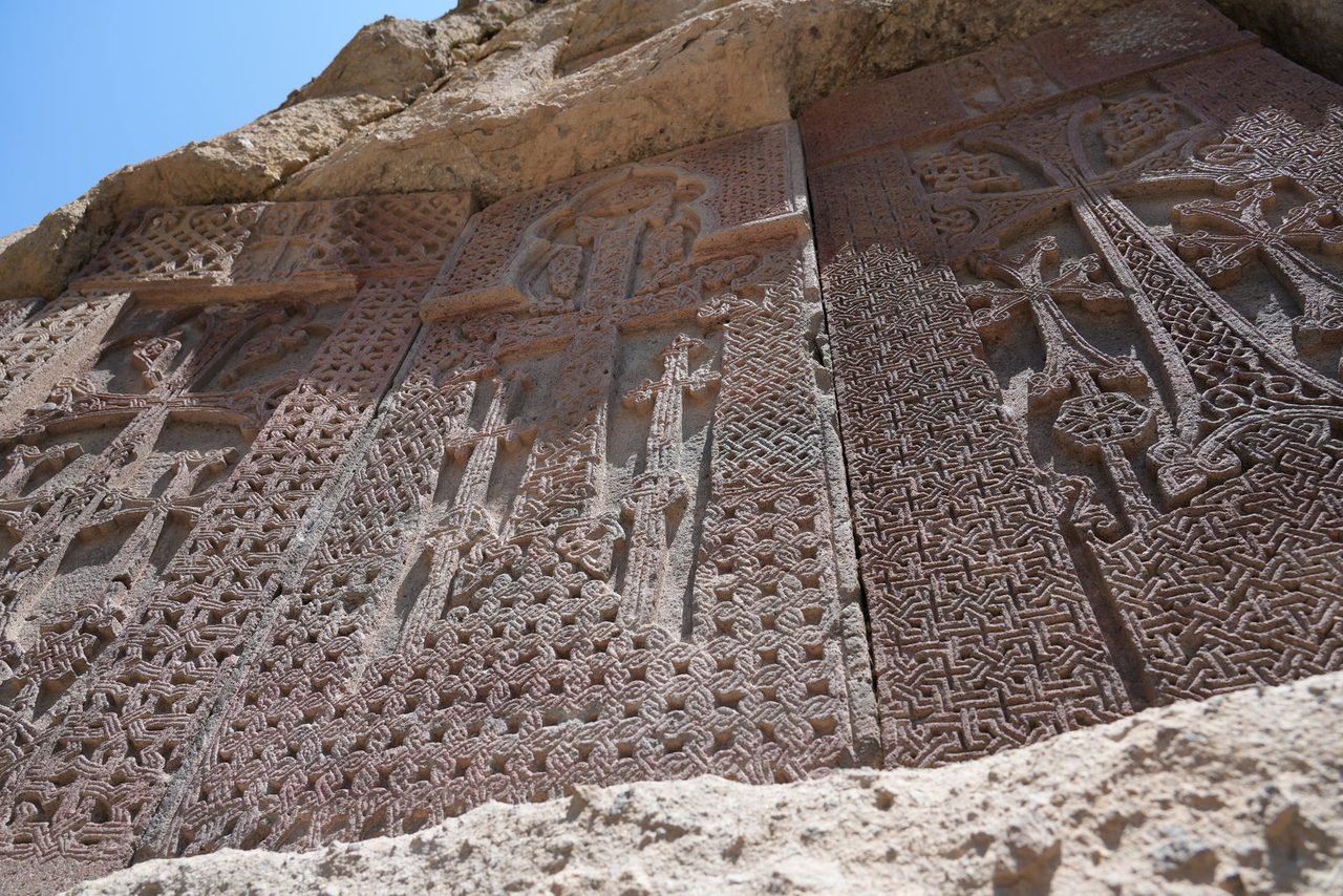 Ancient Khachkars (cross-stones) carved into the rock wall at Geghard