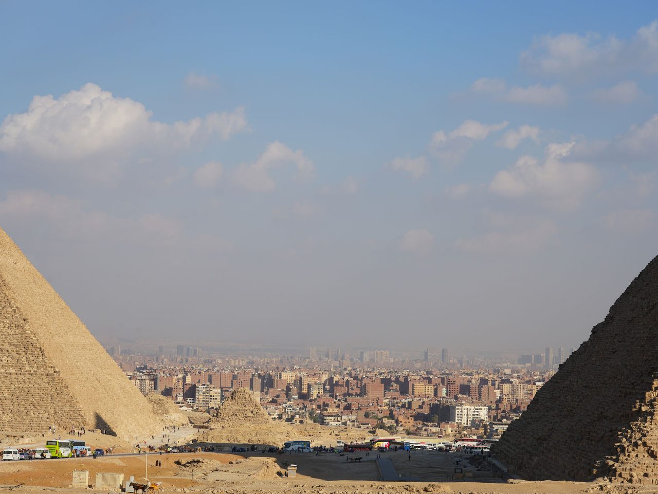 The modern city skyline framed by the ancient Pyramids of Giza