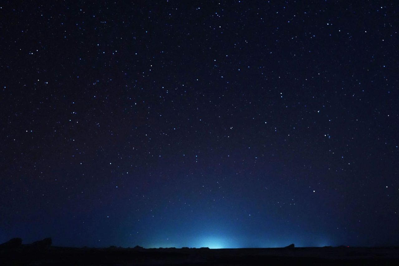 A blue glow whispering beneath the starry skies of the White Desert