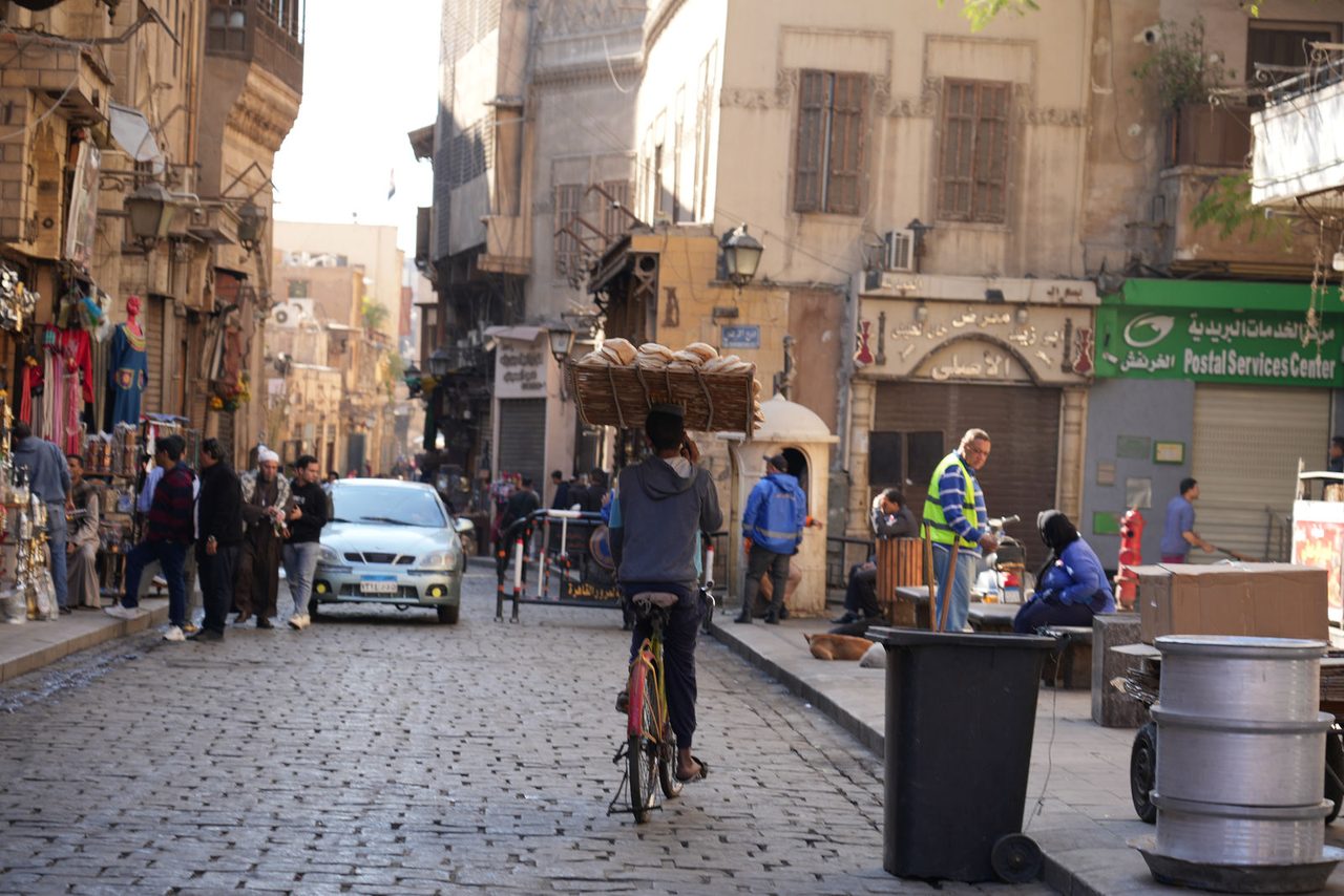 A bread delivery man cycling through the cobblestones of Al-Muizz Street