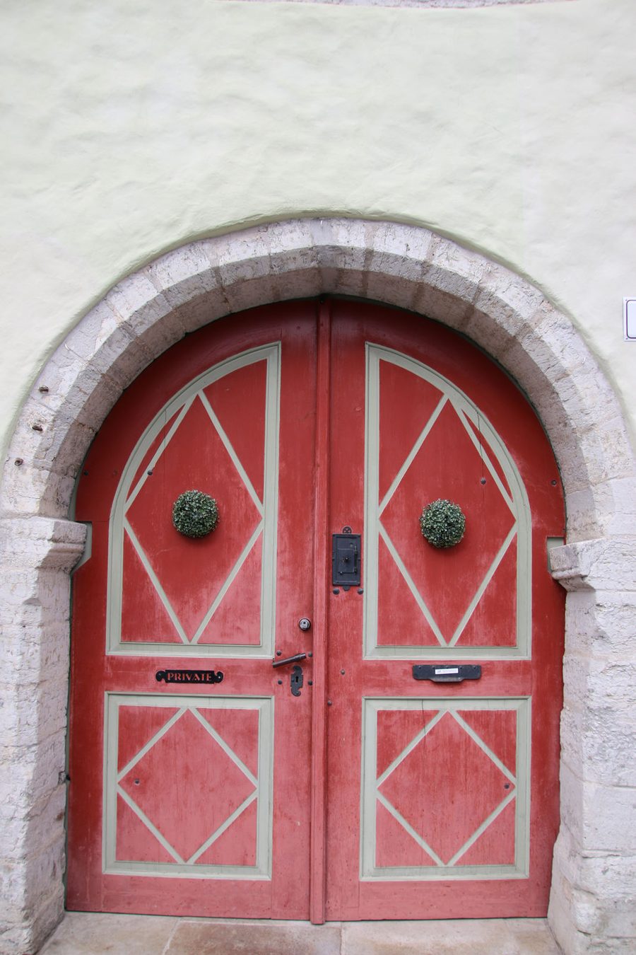 The historic red wooden door with a stone arch