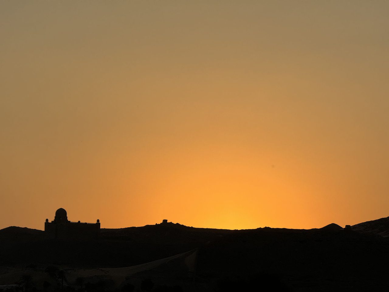 The striking silhouette of the Aga Khan Mausoleum against the sunset glow