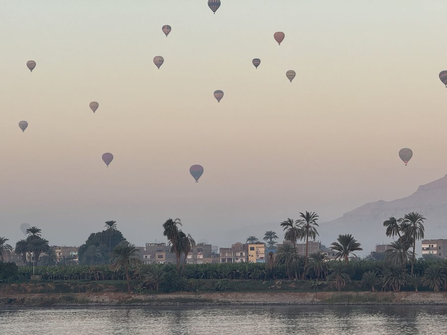 Dozens of hot air balloons rising over the peaceful Nile River at dawn