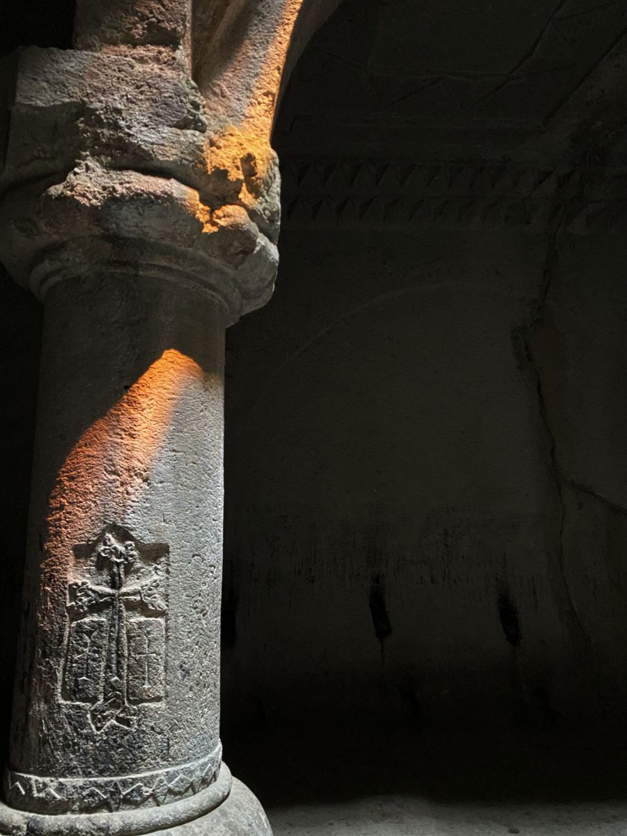 A warm beam of light illuminating the stone column at Geghard