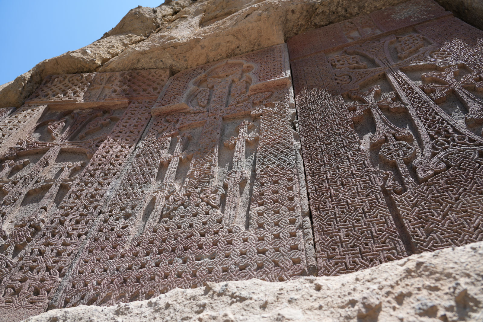 Ancient Khachkars (cross-stones) carved into the rock wall at Geghard