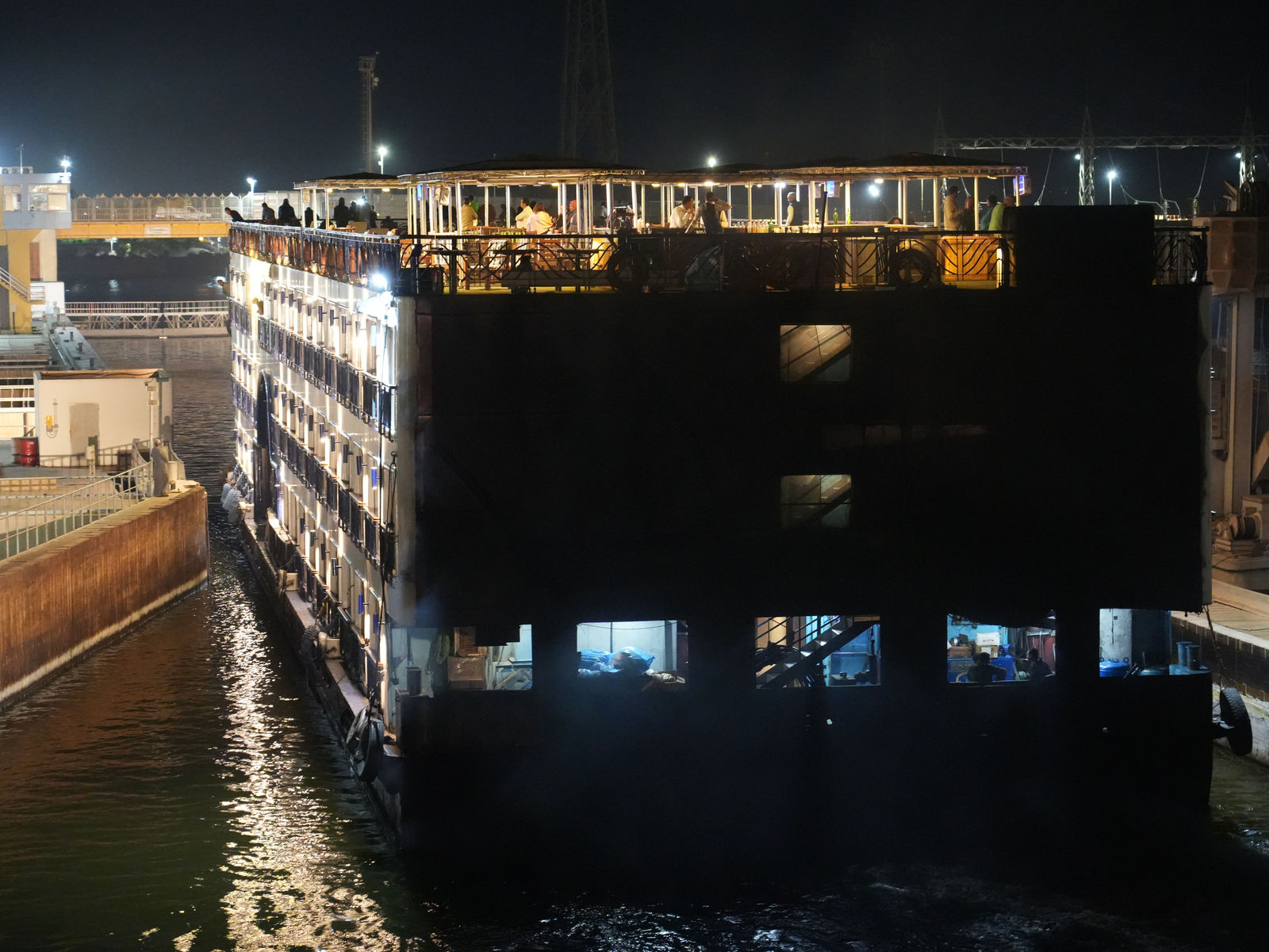 A grand cruise ship passing through the historic Esna Lock at night