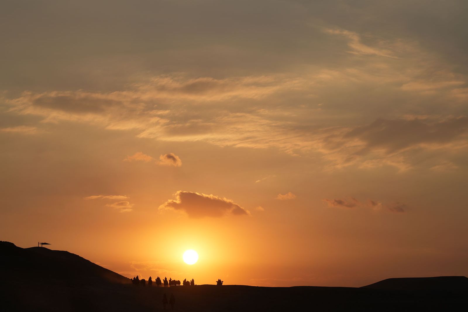 Silhouettes of riders walking into the sunset glow of the Giza Desert