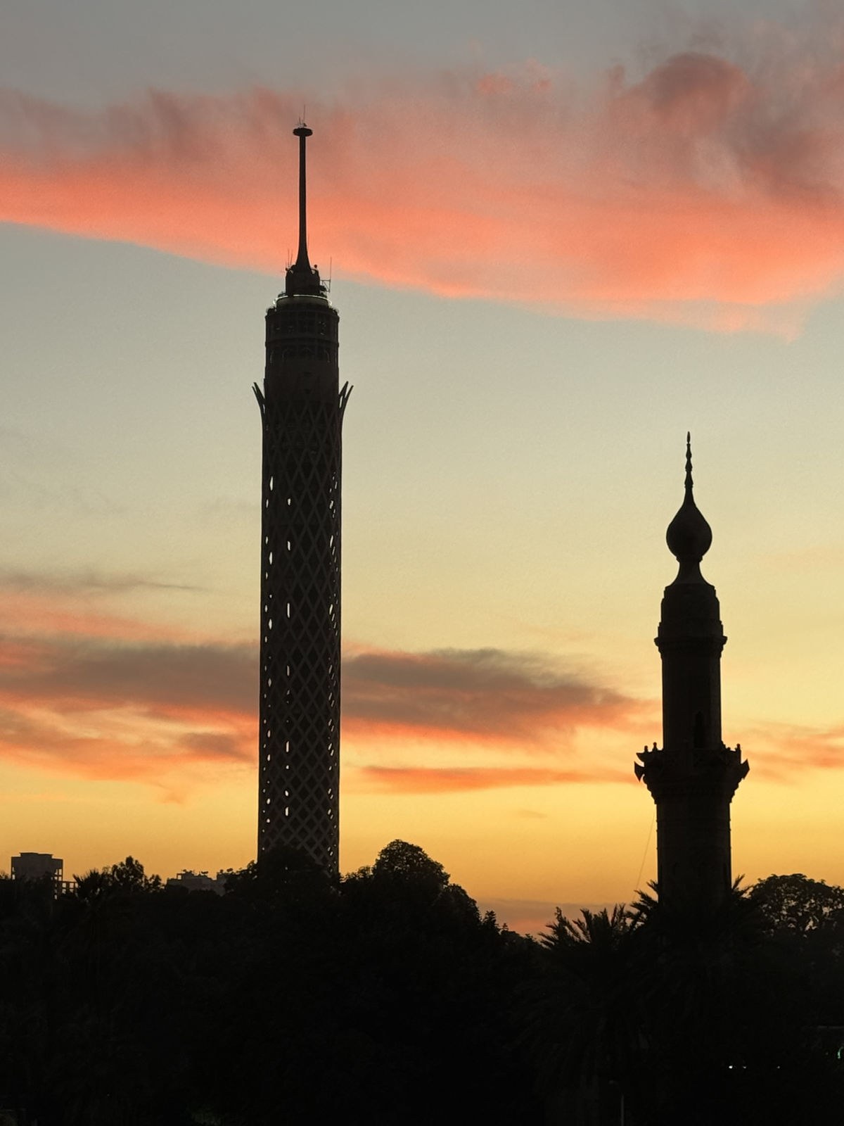 The beautiful silhouette of the Cairo Tower and a historic minaret at sunset