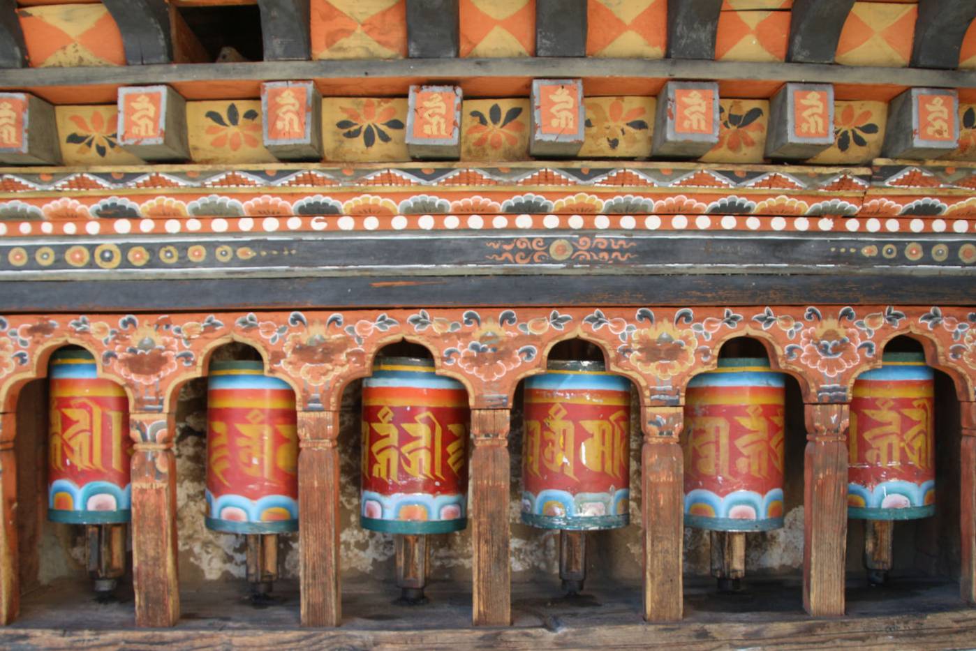 A row of colorful Buddhist prayer wheels at Kyichu Lhakhang