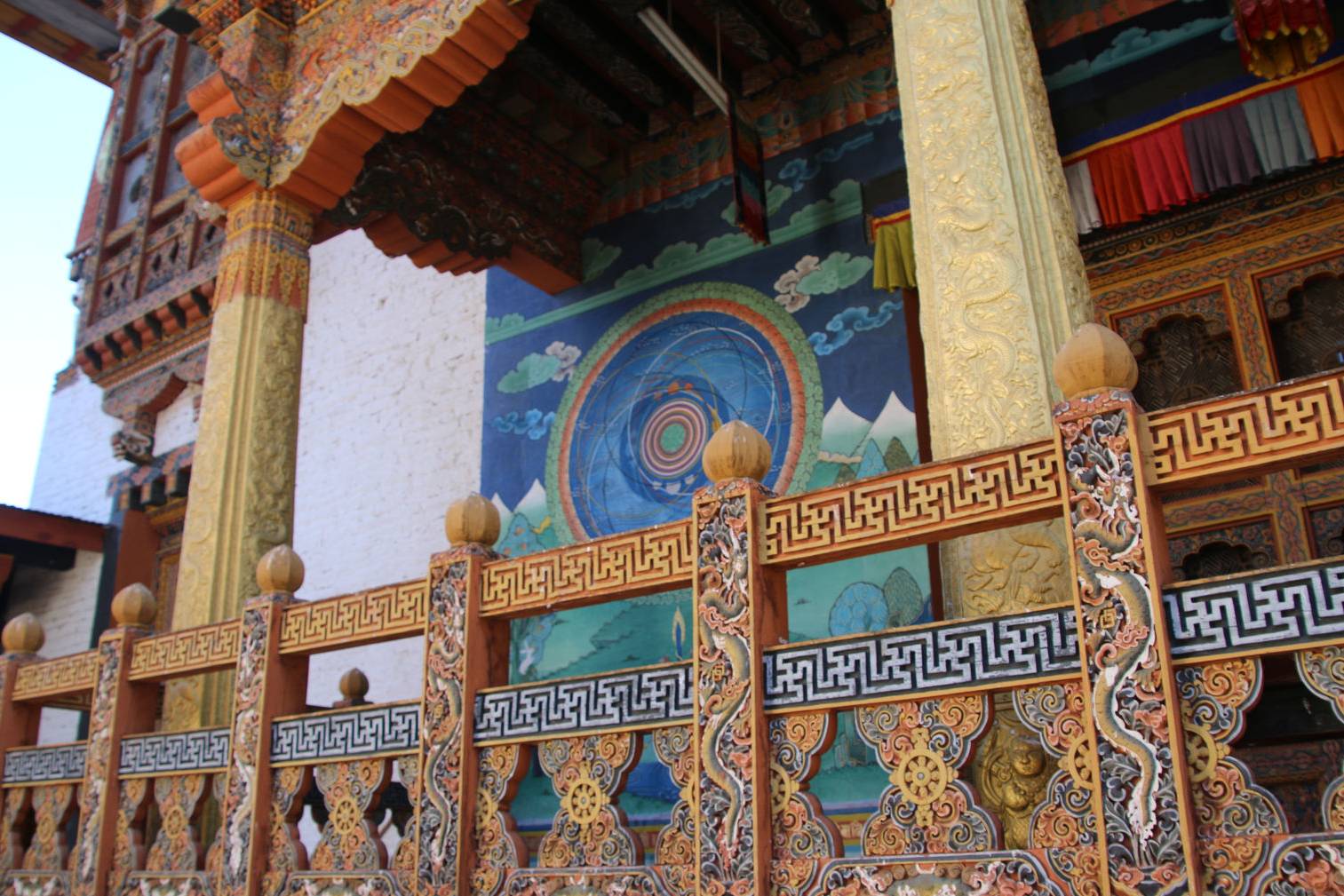 A vibrant Buddhist mural and ornate railings at Punakha Dzong