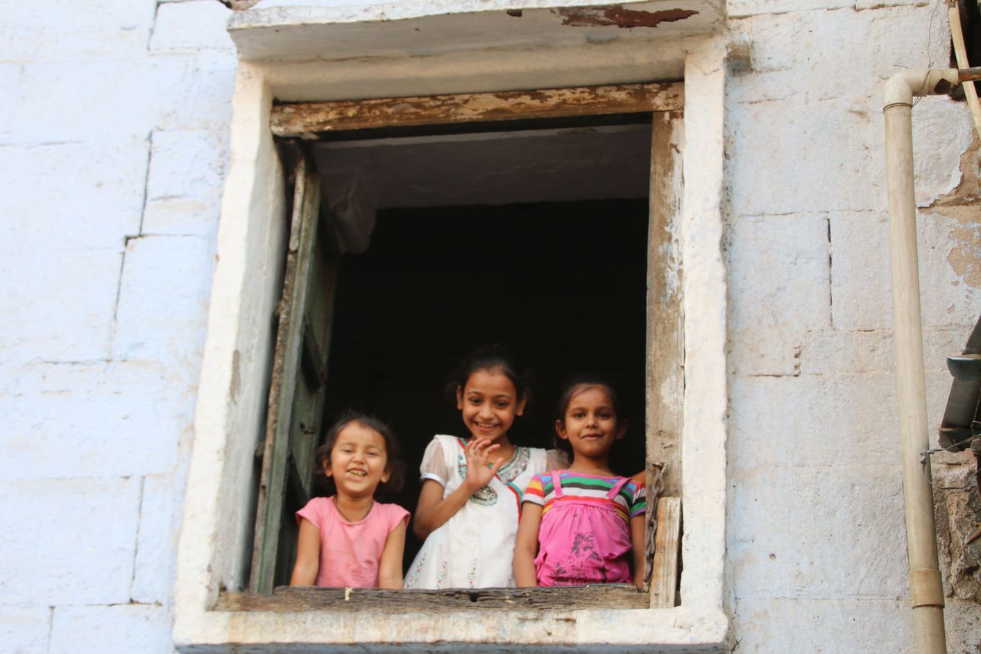 Children waving from a window in the Blue City