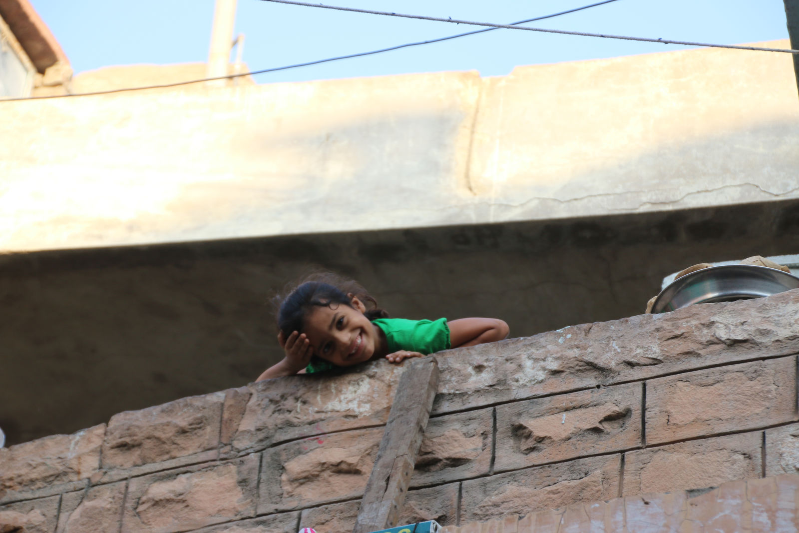 Child waving from a window in the Blue City