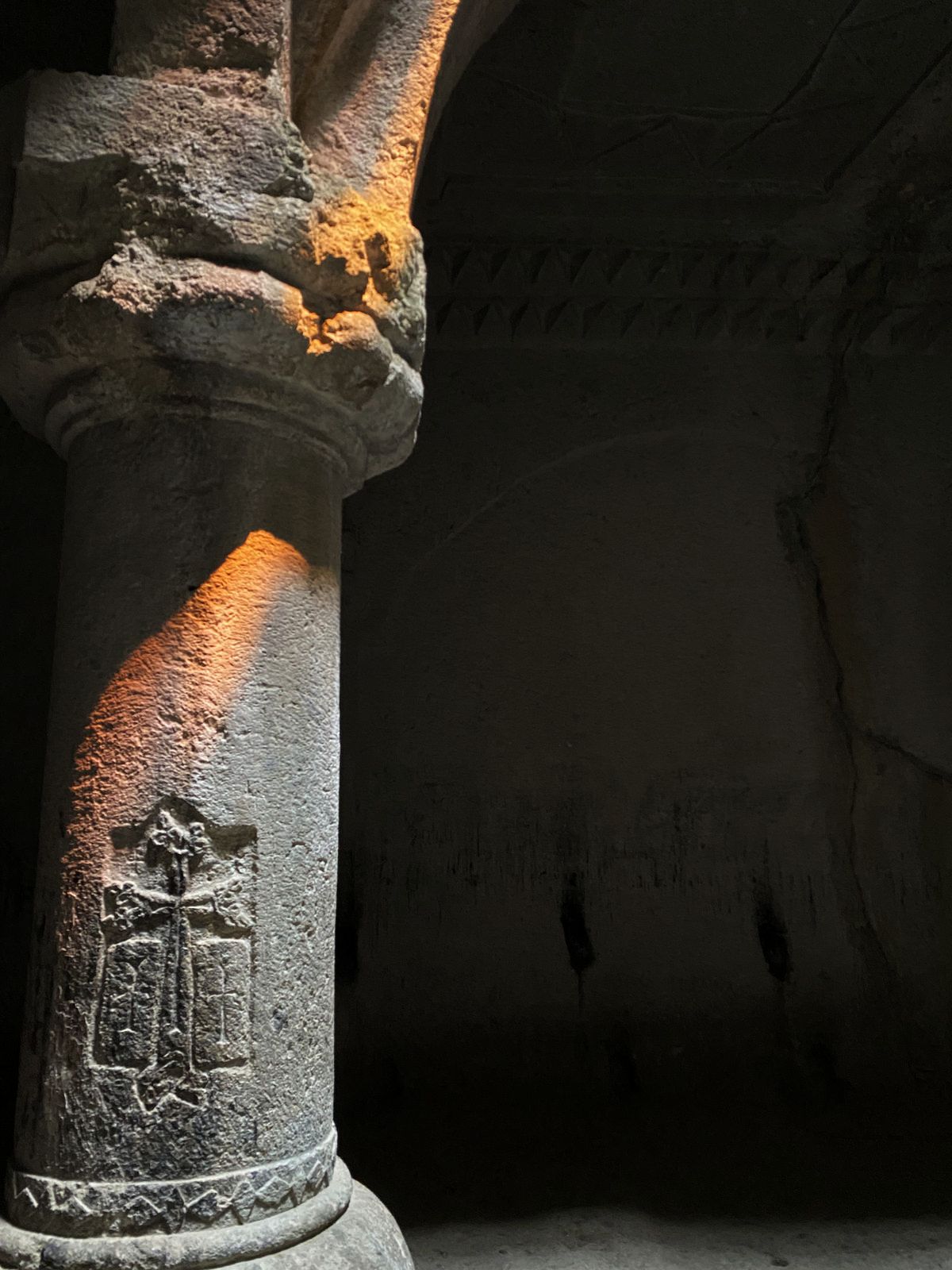 A warm beam of light illuminating the stone column at Geghard